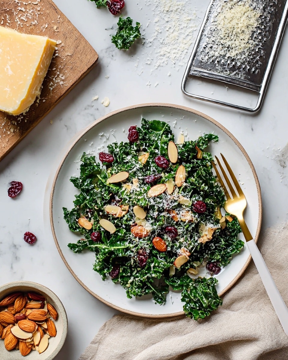The dish shows a white plate with a fresh kale salad mixed with dark green, chopped kale leaves, and scattered light brown almond slices on top. There are also small pieces of dried red cranberries and a sprinkle of grated white cheese spreading evenly over the salad. A gold and white fork lies on the right edge of the plate with a small amount of kale on its prongs. The plate rests on a white marbled surface, next to a beige cloth. Above the plate, a block of hard cheese, a metal grater with cheese crumbs, and a small bowl with almond slices are placed. Photo taken with an iphone --ar 4:5 --v 7