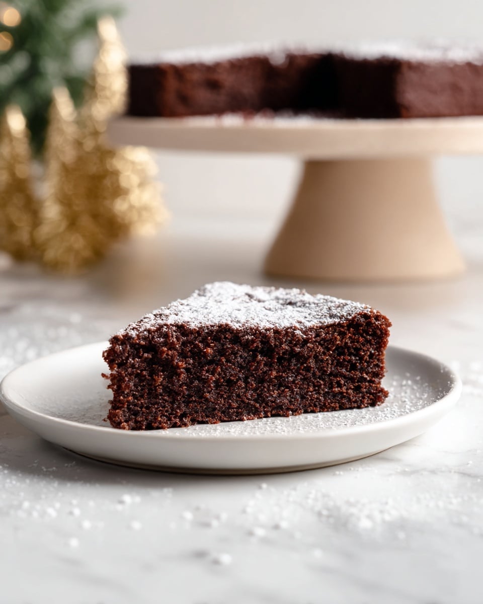 A single slice of thick, moist chocolate cake sits on a simple white plate, the cake’s dark brown crumb showing a soft, slightly crumbly texture. Light white powdered sugar is dusted evenly on top of the slice, with a few scattered outside the plate on the white marbled surface. In the background, more cake slices rest on a beige cake stand that elevates them above the surface. Soft out-of-focus golden decorative trees add a warm festive feel to the scene. The photo taken with an iphone --ar 4:5 --v 7