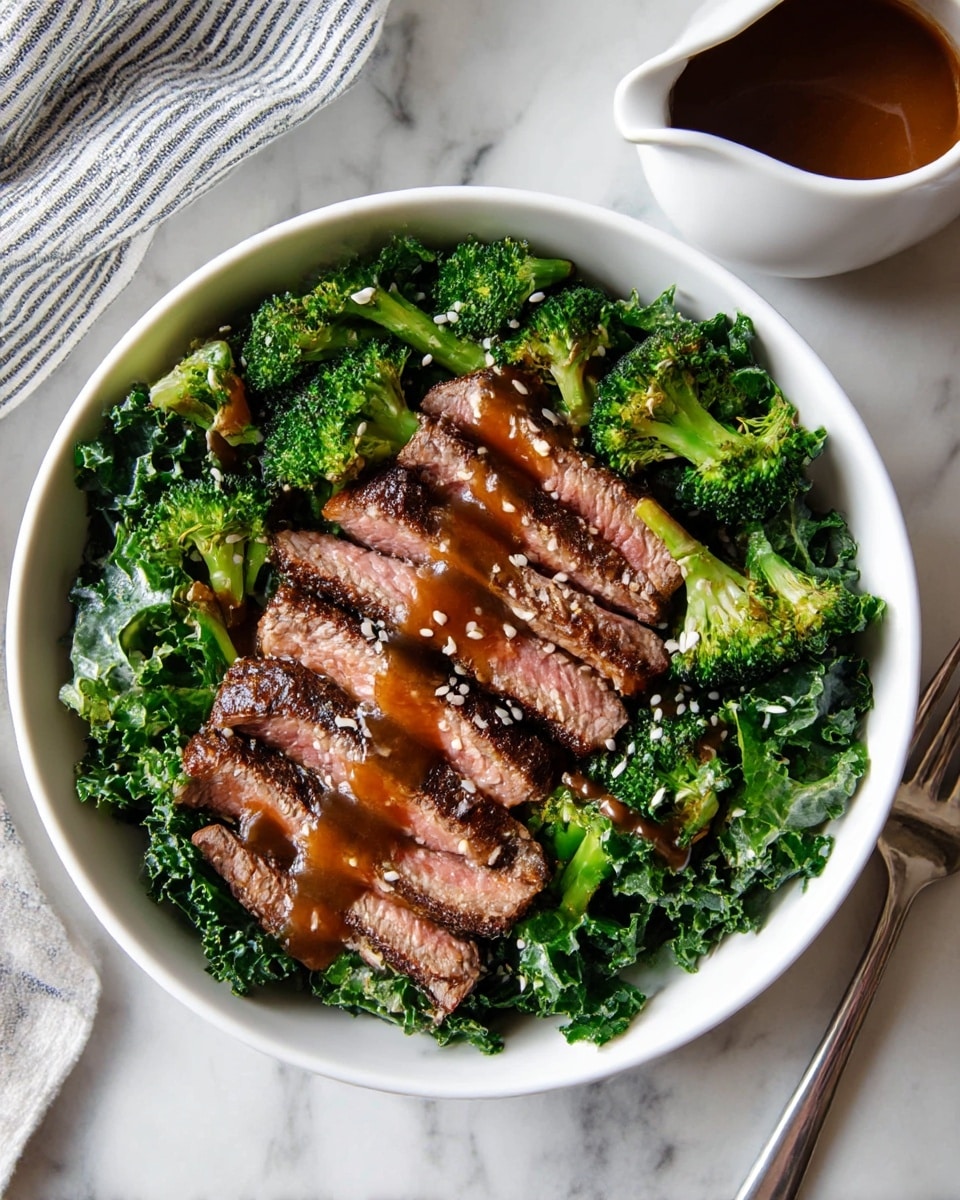 A white bowl sits on a white marbled surface, filled with a fresh salad with three main layers. The bottom layer is made of curly kale leaves in deep green color, forming a rough and leafy bed. The middle layer has bright green roasted broccoli florets with slight charring on the edges, scattered evenly on top of the kale. The top layer features several slices of grilled steak, cooked medium with a pink center and dark brown, slightly charred edges, laid neatly across the top. The whole dish is drizzled with a glossy brown sauce and sprinkled with white sesame seeds. A fork with a silver handle rests on the surface beside the bowl, and a white sauce pitcher filled with brown sauce sits in the upper right corner. A striped cloth is partially visible near the edge. photo taken with an iphone --ar 4:5 --v 7