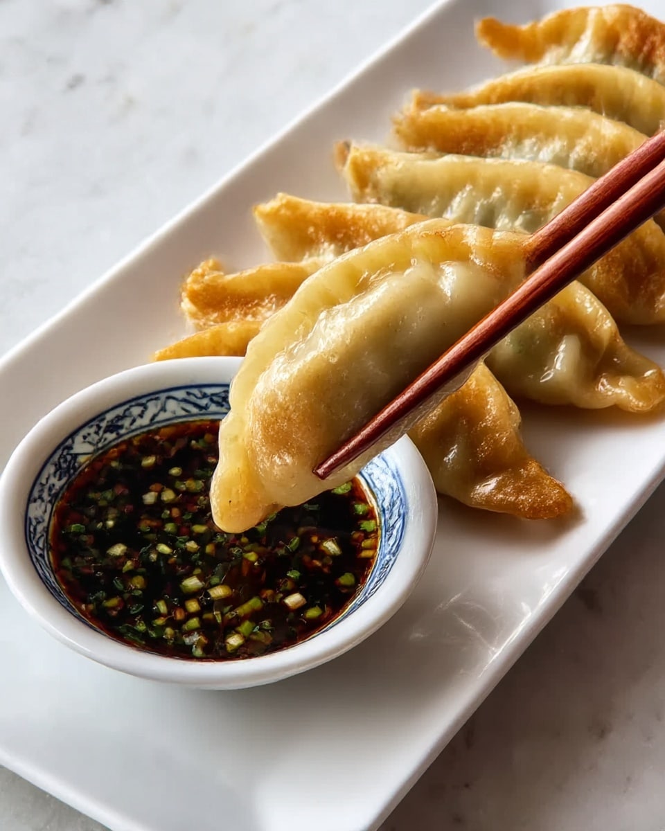 A white rectangular plate on a white marbled surface holds seven golden brown dumplings arranged in two rows. One dumpling is held by a pair of brown chopsticks dipping into a small white bowl with a blue pattern on its rim. The bowl is filled with dark soy sauce mixed with small green and white bits. The dumplings have a shiny and slightly crispy texture. Photo taken with an iphone --ar 4:5 --v 7