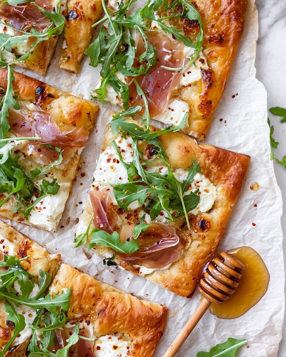 The image shows a flatbread pizza cut into several rectangular slices placed on parchment paper over a white marbled surface. The base is golden brown and crispy with a slightly puffed edge. The first layer has melted white cheese spread evenly, while the second layer includes thin slices of light pink prosciutto scattered across the pizza. The third layer is fresh green arugula leaves spread freely on top, adding a bright contrast. A thick honey glaze with red pepper flakes is drizzled unevenly across the pizza and a wooden honey dipper rests on the parchment paper, dripping honey onto one slice. The scene is bright and fresh, capturing the texture and colors clearly. photo taken with an iphone --ar 4:5 --v 7