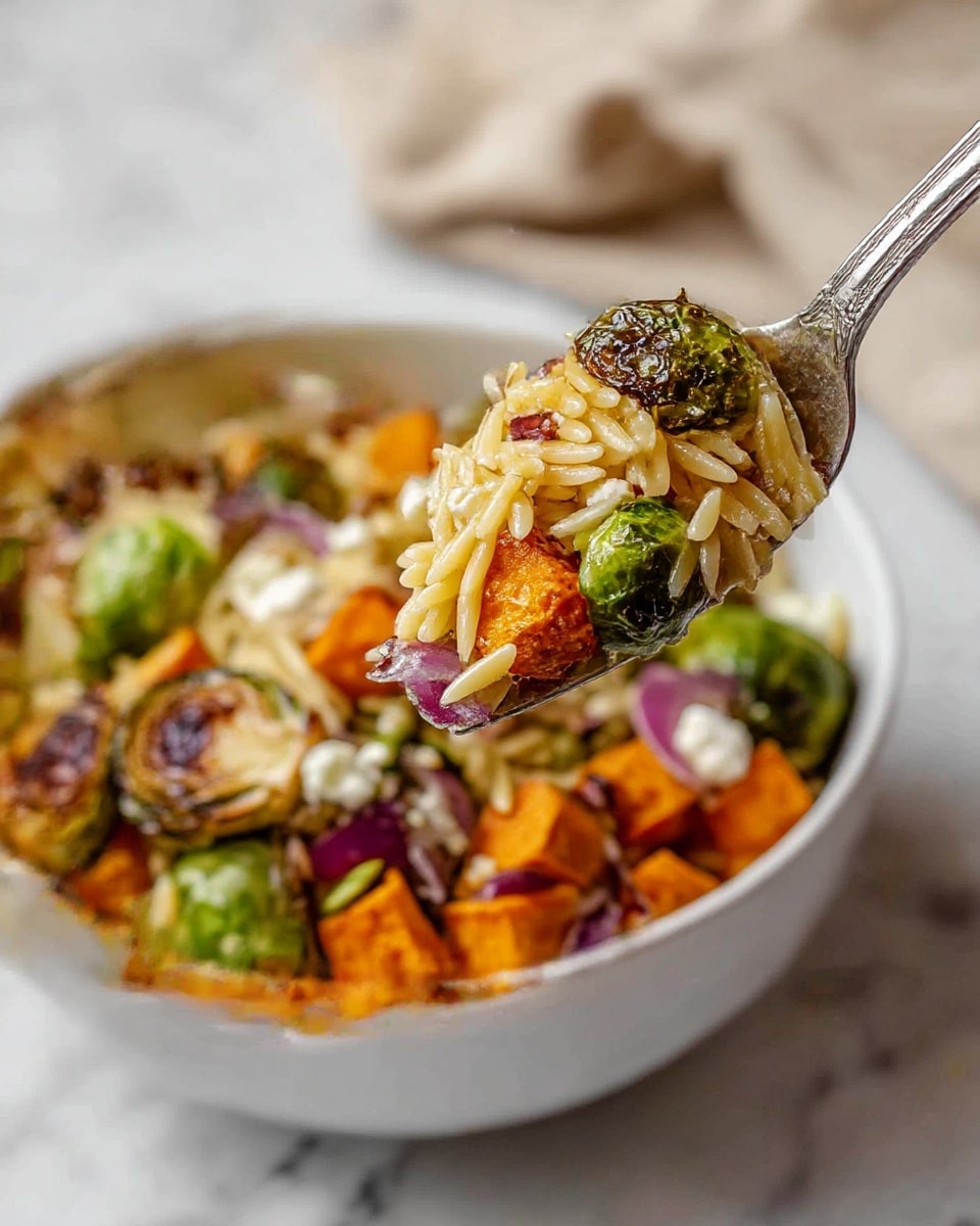 A white bowl filled with a layered salad. The bottom layer has roasted orange sweet potato cubes scattered evenly. On top of this, there are charred green brussels sprouts with a rough texture. Sliced red onions add purple shades mixed in the layers. The main top layer shows golden orzo pasta with a smooth, slightly shiny surface. Small dots of white creamy cheese are spread throughout. A silver fork lifts a bite showing all these layers mixed together over a white marbled surface. A beige cloth is softly blurred in the background. Photo taken with an iphone --ar 4:5 --v 7