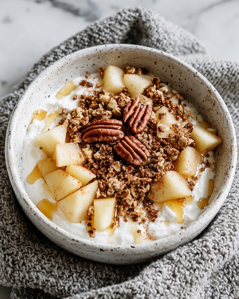 A white speckled bowl is filled with a thick white cottage cheese base as the first layer, topped with small light yellow pear chunks evenly spread around the bowl. On top of the pears, there is a layer of crunchy brown granola scattered with a few whole pecans, which are a darker reddish brown. Golden honey is drizzled all over the bowl, adding a glossy shine and pooling slightly between the toppings. A light dust of cinnamon sprinkled on top adds a warm touch to the dish. The bowl sits on a soft gray knitted cloth over a white marbled surface. Photo taken with an iphone --ar 4:5 --v 7