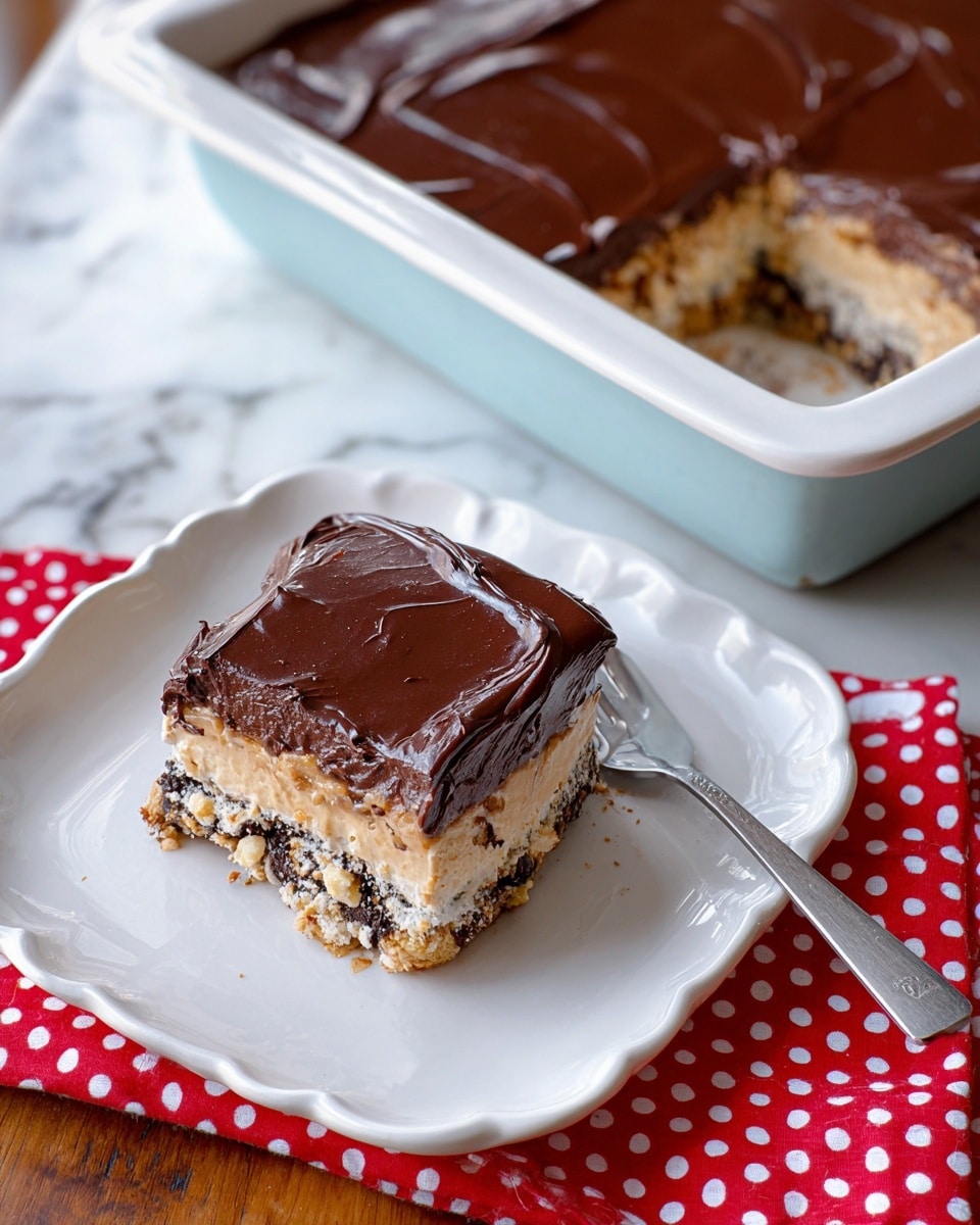 A square piece of layered dessert is placed on a white square plate, showing three layers: the top layer is a smooth and shiny dark brown chocolate frosting, the middle layer is light beige cream with visible cookie bits, and the bottom layer looks like dark crushed cookies mixed with nuts, creating a crunchy texture. The dessert piece sits on a white scalloped edge plate with a red and white polka dot cloth underneath, and a silver fork rests nearby. The remaining dessert with a missing square piece is in a white rectangular baking dish, revealing the same three layers inside. The whole setting is on a white marbled surface, showing warm, natural light. photo taken with an iphone --ar 4:5 --v 7