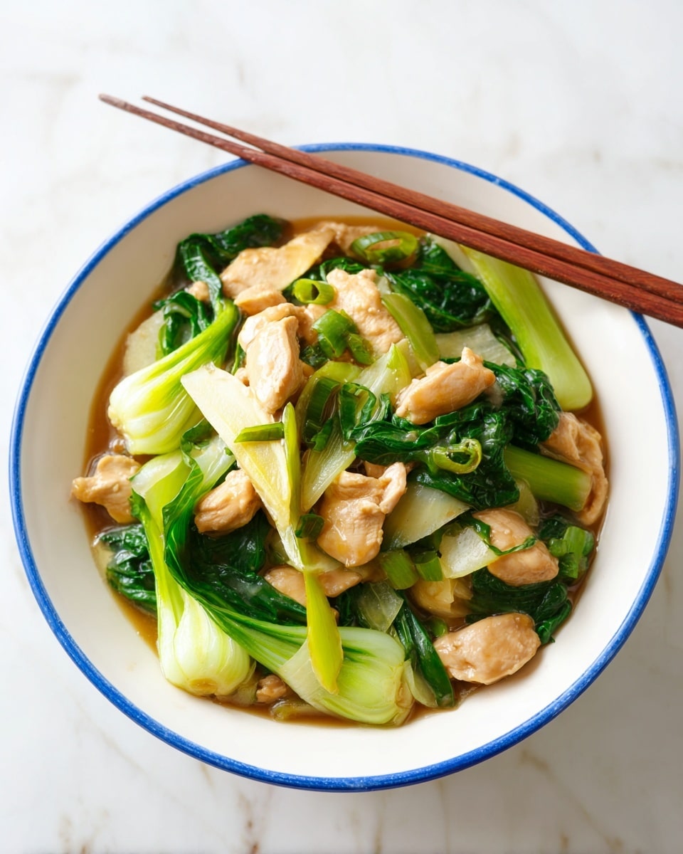 A white bowl with a blue rim filled with a stir fry dish, showing three main layers: tender light brown chicken pieces that look juicy, bright green bok choy with both leaves and stalks, and slices of light tan ginger. The ingredients sit in a thin brown sauce that lightly coats the food. A pair of wooden chopsticks rests on the rim of the bowl. The bowl is set on a white marbled surface. photo taken with an iphone --ar 4:5 --v 7